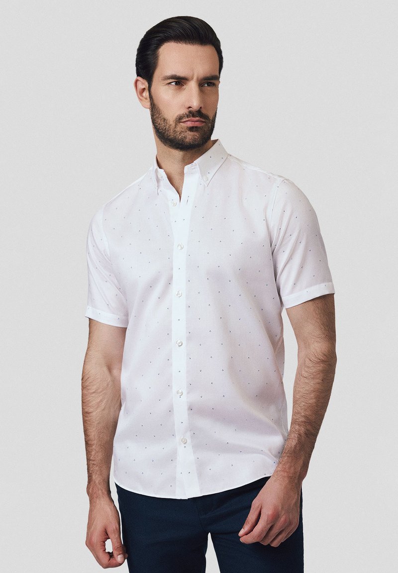 Biała koszula z krótkim rękawem z kołnierzykiem zapinanym na guziki, ozdobiona wzorem małych niebieskich kropek. Gładka tkanina i standardowy krój.