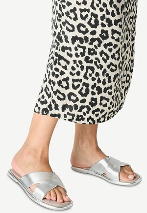 Zilveren cross-band slide sandalen met een platte zool. Gladde metallic afwerking, open teen ontwerp. Draag met een knielange dierenprint rok.