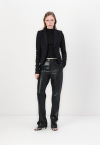Black tailored blazer over a black fitted top, paired with high-waisted black leather trousers. Simple design, smooth texture, minimal hardware.