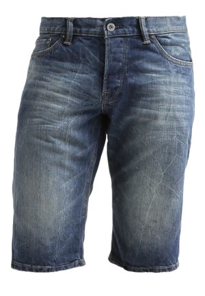 Sort grafisk t-shirt med tegneseriedesign, kombineret med blå denimshorts og sorte sneakers. En brun rygsæk fuldender outfittet.