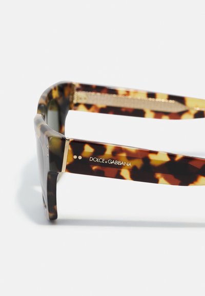Cigányhéj napszemüveg, téglalap alakú kerettel, arany díszítéssel a szárnál, és fehér "DOLCE & GABBANA" logóval. Texturált felület.