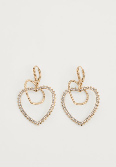 Boucles d'oreilles en forme de cœur doré, avec deux cœurs se chevauchant, ornées de petits strass clairs le long des bords.