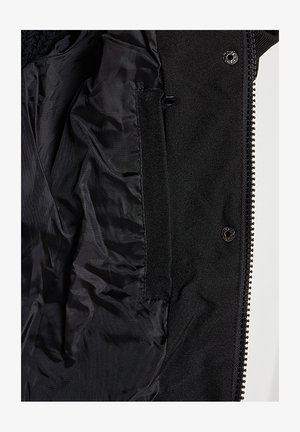 Interieur van een zwart jack met een gladde voering, voorzien van een zak en een ritssluiting langs de rand. Zachte textuur, weinig details.