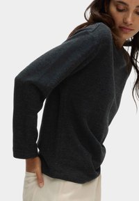 Ciemnoszary sweter z okrągłym dekoltem, długimi rękawami i luźnym krojem. Miękka struktura i minimalne detale szycia.