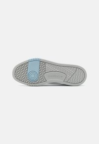 Fehér és világoskék gumitalpú Reebok sneaker, texturált tapadós mintázattal, kör alakú logóval és kontrasztos kék részlettel.