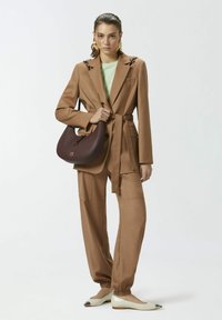 Smeđi odijelo s remenom, zeleni top i burbonska torba. Sadrži široke hlače, elastične manžete i cipele s oštrim vrhom sa srebrnim detaljima.