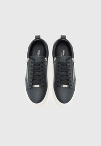 Schwarze Sneaker aus strukturiertem Leder, mit Schnürdesign, seitlichen Reißverschlüssen und weißen Gummisohlen. Innen mit „ANTONY MADE IN.“ beschriftet.