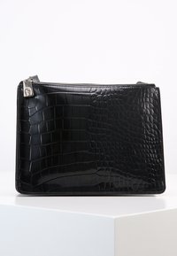 Borsa a tracolla in ecopelle nera con texture a coccodrillo, dotata di una cerniera argentata e un piccolo logo decorativo sul tiralampo.