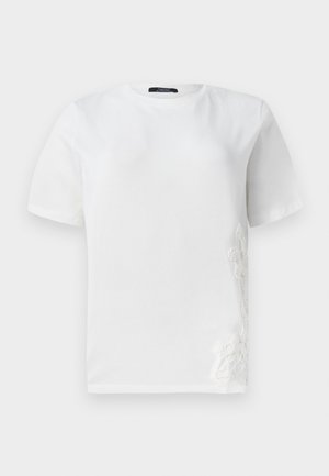 Valkoinen puuvillapaita, jossa on lyhyet hihat, pyöreä pääntie ja koristeellinen pitsivuoraus vasemmalla puolella. Sileä rakenne, rento muotoilu.