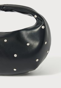 Czarna skórzana torebka o zaokrąglonym kształcie, z gładką fakturą i ozdobiona srebrnymi ćwiekami na całej powierzchni.