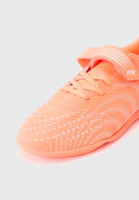 Φωτεινό αθλητικό παπούτσι κοραλλί με υφή στο επάνω μέρος και μοτίβο από λευκές κουκκίδες, καθώς και λουράκι με βέλκρο. Κλείσιμο με κορδόνια για ασφαλή εφαρμογή.