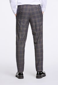 Pantaloni a righe in tonalità marrone e blu, realizzati in tessuto testurizzato, dotati di due tasche posteriori con bottone e design a gamba affusolata.