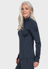 Navyblaues Langarmoberteil mit hohem Kragen, aus feuchtigkeitstransportierendem Material hergestellt. Verfügt über ein Logo am Ärmel und ein figurbetontes Design.