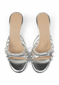 Srebrne sandały open-toe z gładkim metalicznym wykończeniem, z wieloma paskami i detalem w postaci kokardy z przodu. Solidna płaska podeszwa.