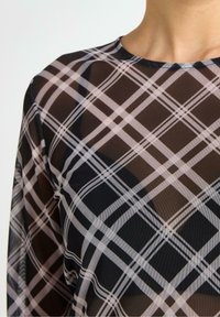 Top trasparente con un motivo a quadri bianco e nero, scollatura rotonda e tessuto leggero con una superficie liscia.