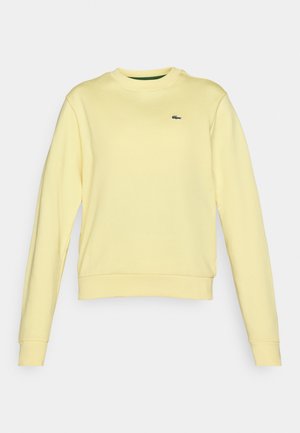 Sudadera amarilla clara hecha de algodón suave, con mangas largas, un cuello redondo y un pequeño logo bordado en el pecho.