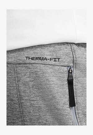 Szary pasek od spodni dresowych Therma-Fit z czarnym przeszyciem i detalem zamka. Miękka tkanina o lekkiej fakturze z wyraźnie widocznym logo.