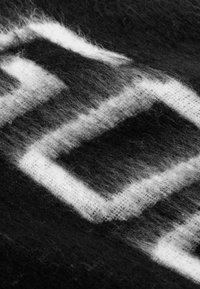 Zwart-witte wollen stof met een geometrisch ruitpatroon, zachte, vuzzy textuur en een mix van sterke en subtiele contrasten.