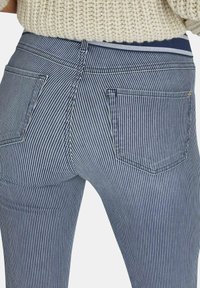 Gestreepte spijkerbroek met een aansluitend ontwerp. Voorzien van een tailleband, twee achterzakken en een combinatie van donkerblauwe en witte strepen.