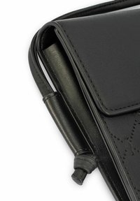 Czarna skórzana torebka o teksturowanej powierzchni, z klapą składana do przodu i starannymi przeszyciami; posiada cienki pasek oraz charakterystyczny element ozdobny.