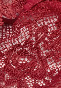 Rode kanten stof met complexe bloempatronen, voorzien van een gestructureerde, open structuur en variërende draaddiktes voor detail en diepte.
