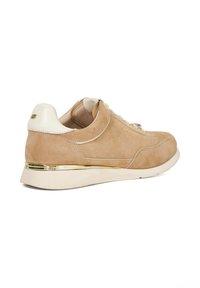 Beige suede sneaker with a white leather heel, gold accent on the sole, round toe, and flat laces. Subtle branding on the side.