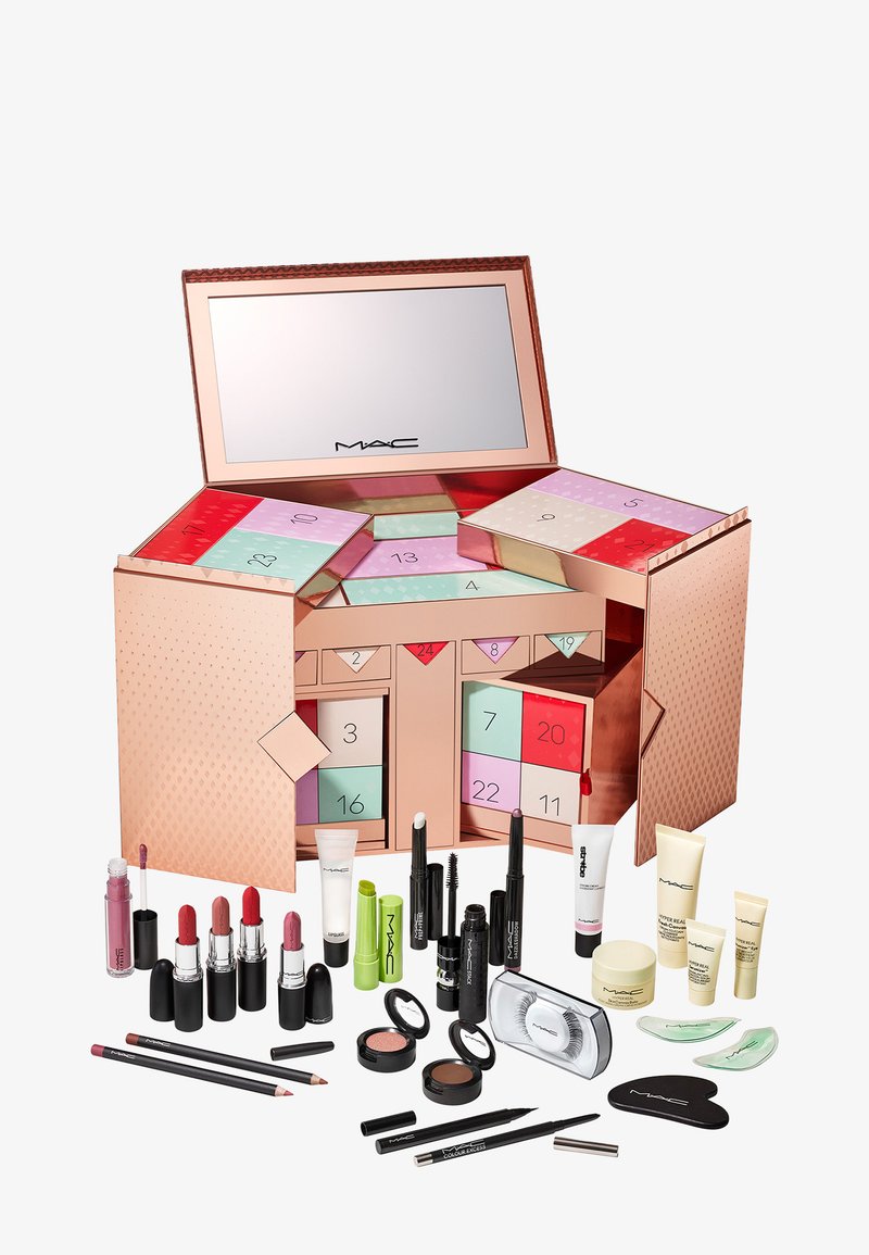 Calendrier de l'Avent en or rose avec un miroir, comportant des compartiments colorés et divers produits cosmétiques MAC, y compris des rouges à lèvres, des eye-liners et des produits de soin.