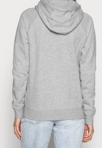 Grå huvtröja med en mjuk fleece-textur, med en känguruficka och ribbat avslut. Designen har en avslappnad passform och raglanärmar.