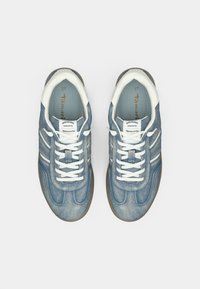 Ζευγάρι μπλε αθλητικών παπουτσιών τύπου τζιν με λευκά κορδόνια και λεπτομέρειες, φωτογραφημένα από πάνω σε άσπρο φόντο.