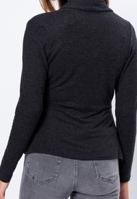 Ciemnoszary top z długim rękawem o miękkiej teksturze i dopasowanym kroju. Posiada szeroki kołnierz i zaokrąglony dół, widoczny od tyłu.