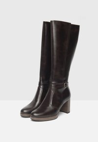 Brown leather knee-high boots with a block heel, featuring a round toe, stitching detail, and a decorative buckle on the ankle strap.