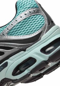 Sportschoen met een bovenwerk van gaas in teal, zilveren accenten en een gestructureerde zwarte zool met zichtbare luchtkussenelementen.