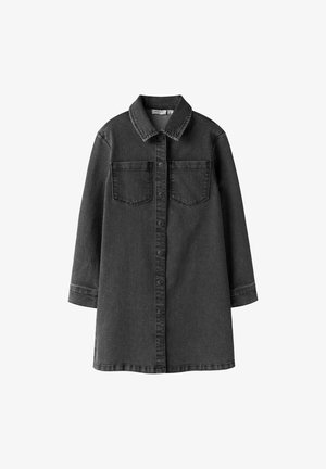 Crna haljina od trapera s kopčanjem na gumbe sprijeda, šiljastim ovratnikom i dva džepa na prsima. Ima duge rukave i ravni kroj.