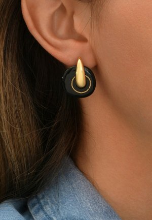 Boucles d'oreilles circulaires noires avec une finition brillante, présentant un accent doré allongé et un délicat détail de anneau doré.