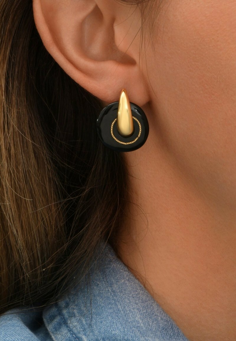 Boucles d'oreilles circulaires noires avec une finition brillante, présentant un accent doré allongé et un délicat détail de anneau doré.