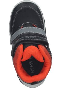 Zwarte sneaker met grijze en rode accenten, voorzien van een klittenbandsluiting, mesh voering en een gevoerde binnenkant. Geox merk zichtbaar aan de binnenkant.