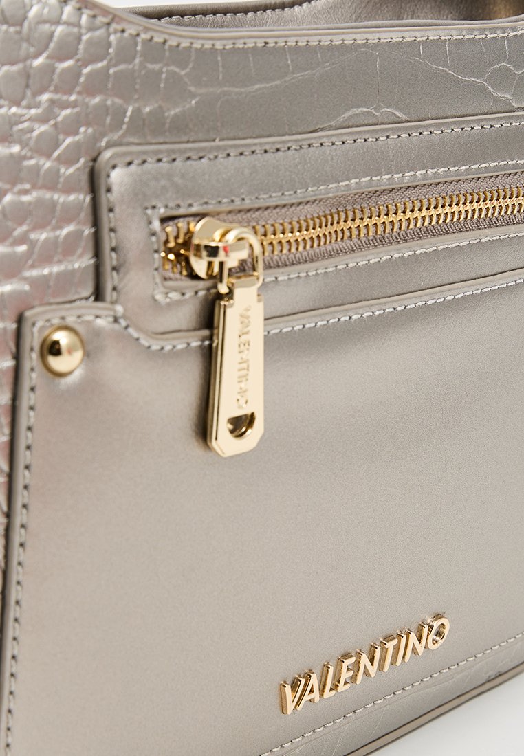 Graue Kunstlederhandtasche mit goldfarbenem Reißverschluss, strukturiertem Oberflächenmaterial und einem Logo-Schild. Elegantes Design mit einem markanten Muster und goldenen Hardware-Elementen.