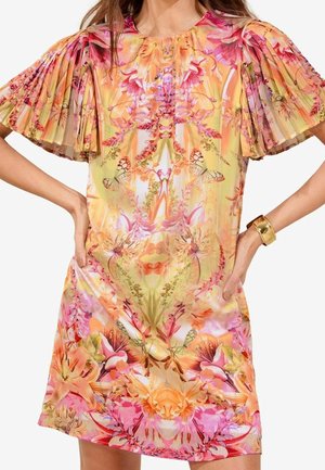 Vrouw draagt een kleurrijke bloemenjurk met geplisseerde korte mouwen met vlindermotief en een gouden armband om haar rechterpols.