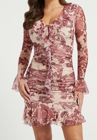 Rimpeljurk van doorschijnende roze stof met kastanjebruine bloemenpatronen, met lange mouwen, een V-halslijn en een uitlopende rok met ruffles.
