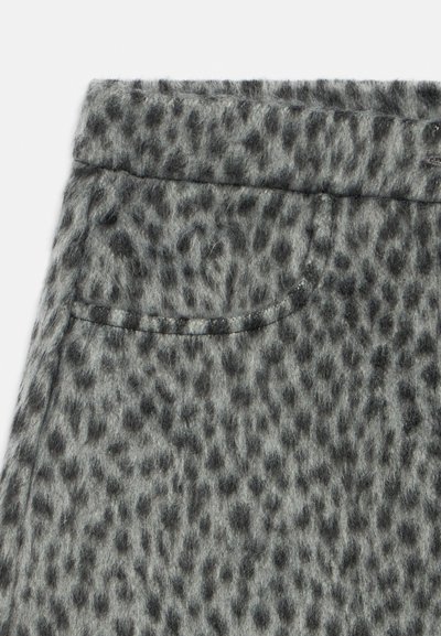 Tissu en laine grise avec motif léopard noir, présentant une poche avant et une couture à la taille sur un vêtement.