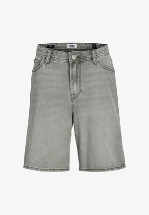 Egy fiú mosolyog, fehér "Botanique Garden" pólót, szürke rövidnadrágot, bézs cipőt, fehér zoknit és barna sapkát visel "Funny Days" szöveggel.