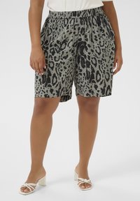 Pilkos ir juodos leopardų rašto šortai, pagaminti iš elastinės medžiagos, su elastinga juosmens juosta ir šoninėmis kišenėmis. Modelis vilki baltas aukštakulnes sandalus.