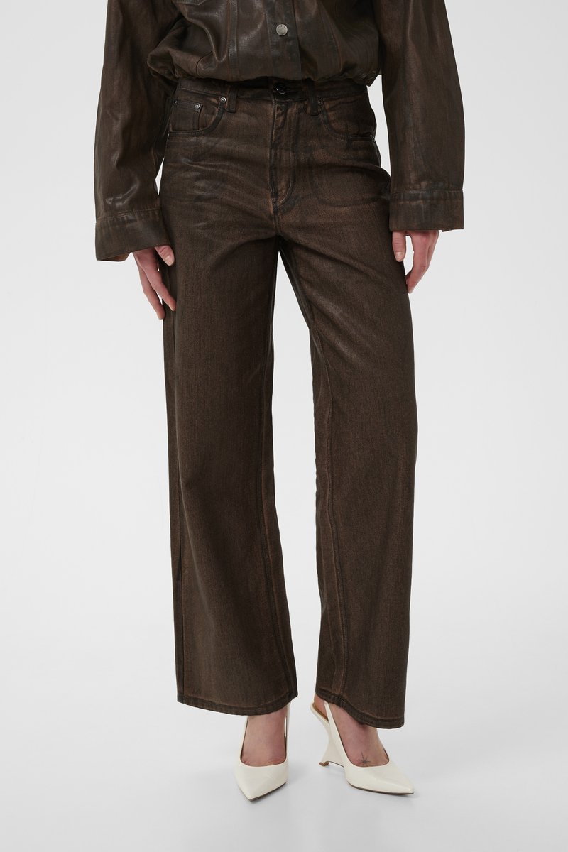 Brown wide-leg jeans with a slightly shiny texture, featuring front pockets, contrasting stitching, and a high waist. Paired with white heels.