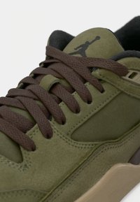Zaļi zamšādas kedas ar brūnajām auklām, gumijas zole un melns Jumpman logo uz mēles. Iezīmējas ar šuvju detaļām un gludu apdari.