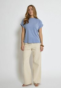 Ljusblå kortärmad t-shirt med rullade ärmar, matchad med krämfärgade vida byxor. Slät tyg med en avslappnad passform. Enkel design.