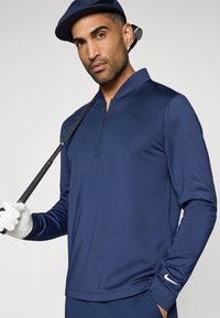 Ναυτικό πόλο μακρύ μανίκι, ελαφρύ ύφασμα, σχέδιο μισού φερμουάρ, υφή, με το λογότυπο της Nike στο μανίκι, συνοδευόμενο από γκολφ κλαμπ και γάντι.