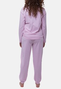 Rosarandigt loungewear-set i bomull som består av en långärmad topp och byxor med elastiska muddar, designad för komfort och rörelsefrihet.