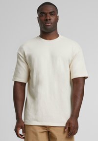 Crème-kleurig katoenen T-shirt met korte mouwen, ronde halslijn en een relaxte pasvorm. Beschikt over een gladde textuur en een minimalistisch ontwerp.