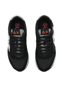 Zapatillas deportivas negras con una parte superior de tela texturizada, acentos laterales blancos y cordones negros. Tienen una lengüeta acolchada y un logo en color naranja.