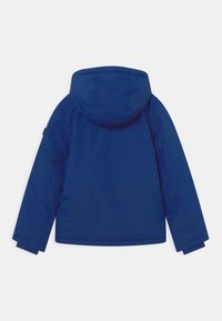 Marineblauwe, waterdichte jas met capuchon, een gladde textuur, elastische manchetten en een rechte snit. Kenmerkt zich door een minimalistisch ontwerp zonder zichtbare branding.